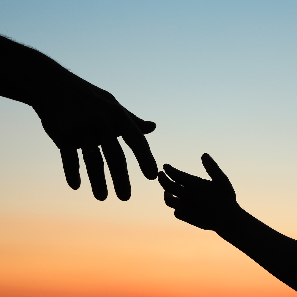 child's hand reaching for grown-up's hand