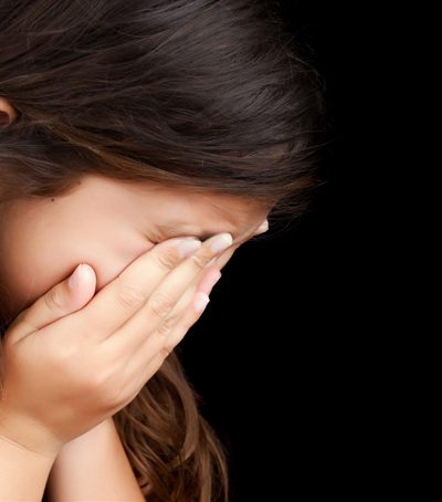 a child holds her face in her hands