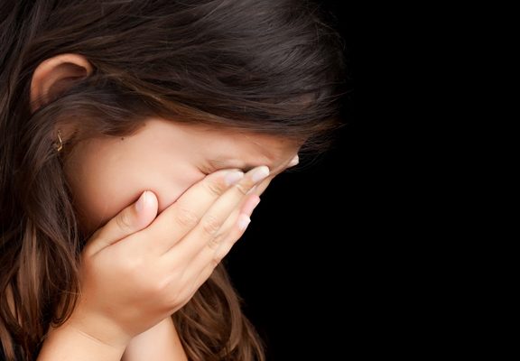 a child holds her face in her hands