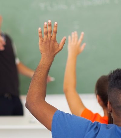 Students raise hands in classroom