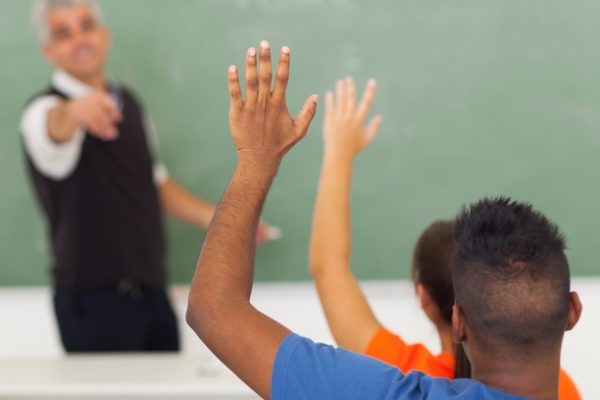 Students raise hands in classroom