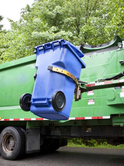 A garbage truck on a tree-lined street.