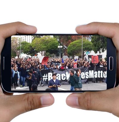Cell phone in hands with Black Lives Matter protest on screen.