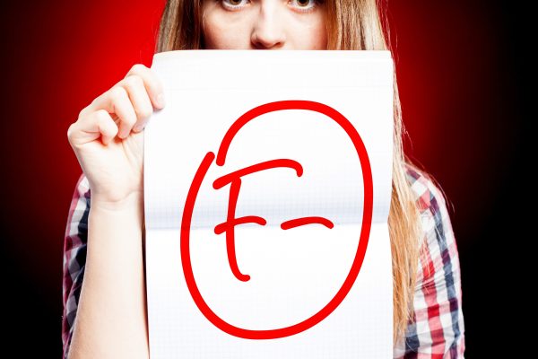 young person holding a graded paper with an 'F'