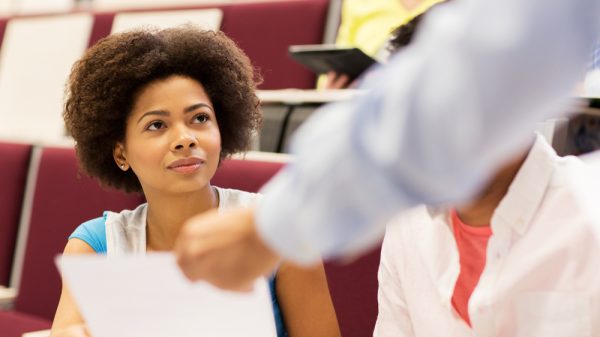 Black woman being handed a piece of paper in a classroom
