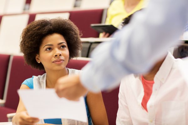 Black woman being handed a piece of paper in a classroom