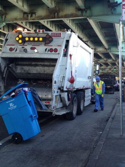 Workers throw homeless people's property into a Caltrans truck