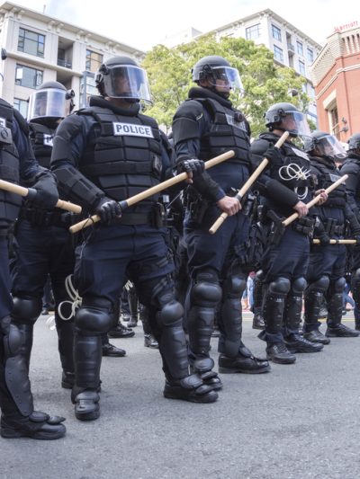 Police in riot gear, holding batons, on a California street
