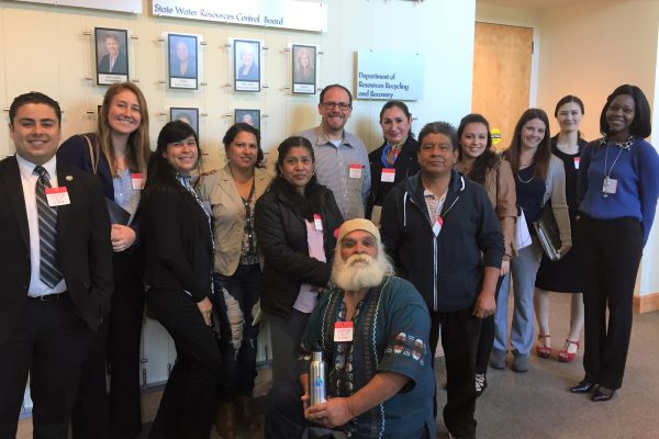 A group of 13 people stands outside the hearing room of the State Water Resources Control Board, ready to provide public comment on the contaminant 1,2,3-TCP