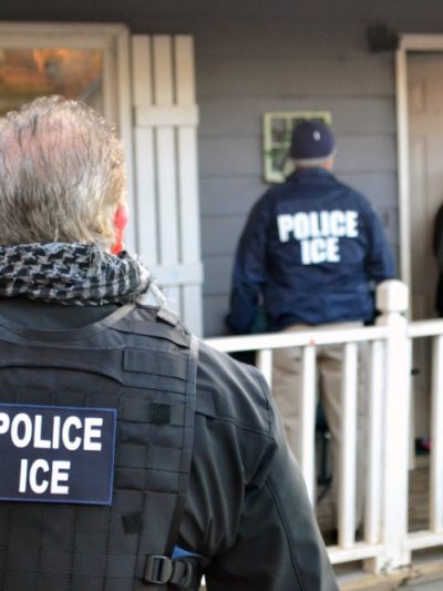 ICE agents standing in front of a home, knocking on the door.