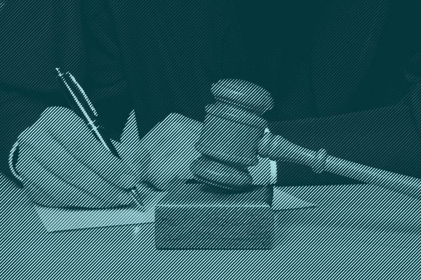 A judge signs papers with a gavel sitting on the desk