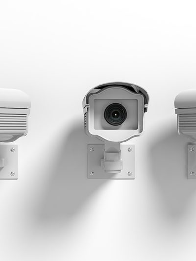Three surveillance cameras on a wall point in three different directions giving the sense of a panopticon