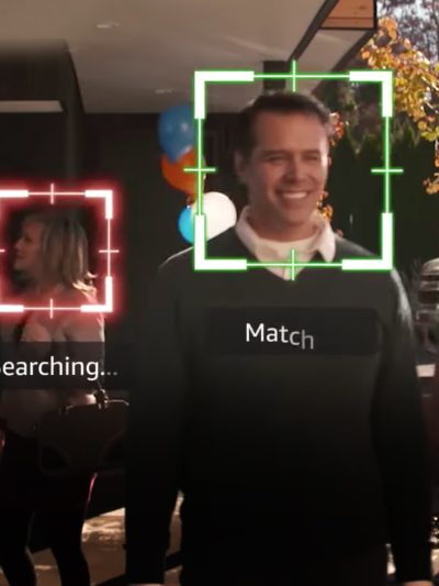 Four people walk down a pathway outside a building while Amazon tracks their faces