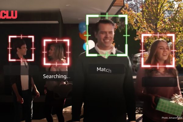 Four people walk down a pathway outside a building while Amazon tracks their faces