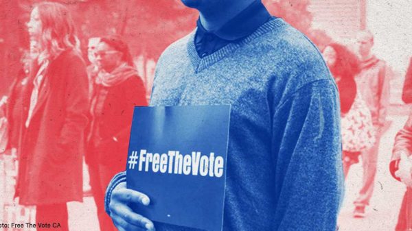 person holding a #freethevote sign in front of a crowd of people
