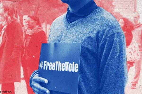 person holding a #freethevote sign in front of a crowd of people