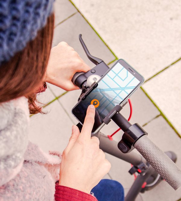 Woman operating mobile application standing atop scooter
