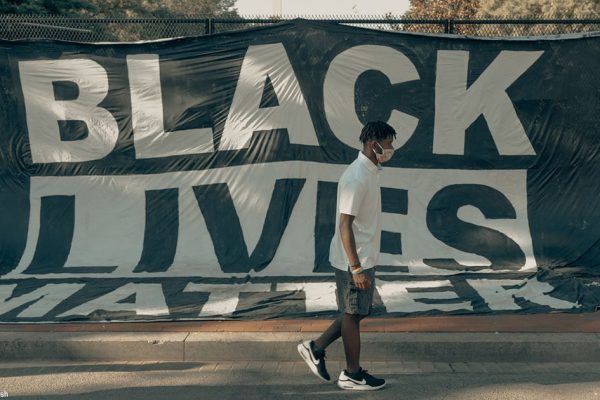 Black student walks by Black Lives Matter sign