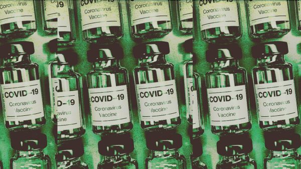 Covid-19 Vaccine vials are stacked on a table. A solid green color is overlaid for a visual affect.