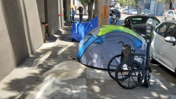 wheelchair beside a tent on a street in San Fransisco