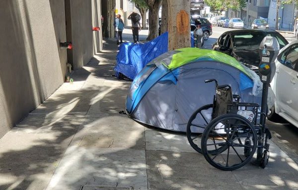 wheelchair beside a tent on a street in San Fransisco