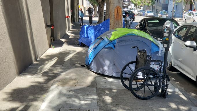 wheelchair beside a tent on a street in San Fransisco