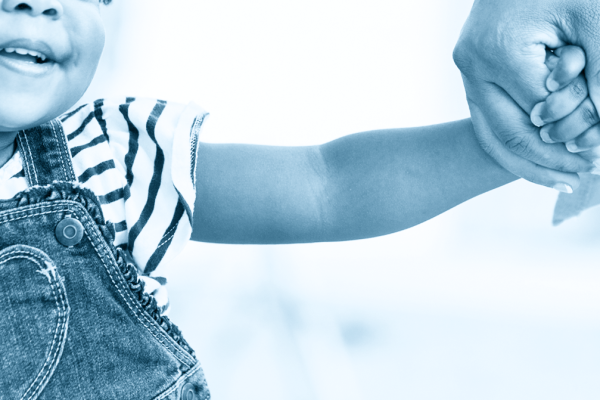 A photo of a young child holding her mother's hand.