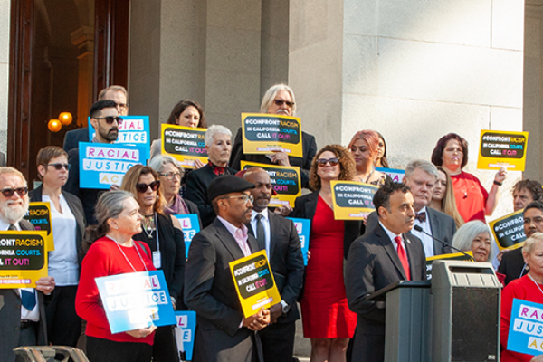 Group of people around a speaker infront of a capital building
