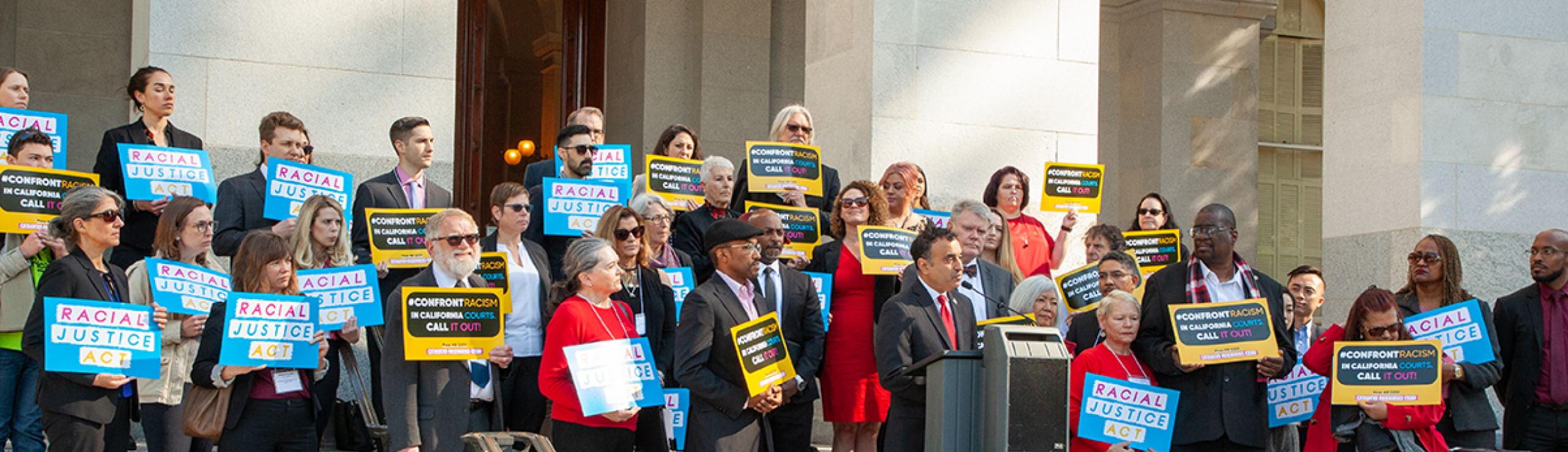 Group of people around a speaker infront of a capital building