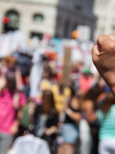 raised fist in forground at a protest