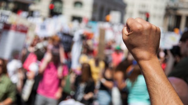 raised fist in forground at a protest