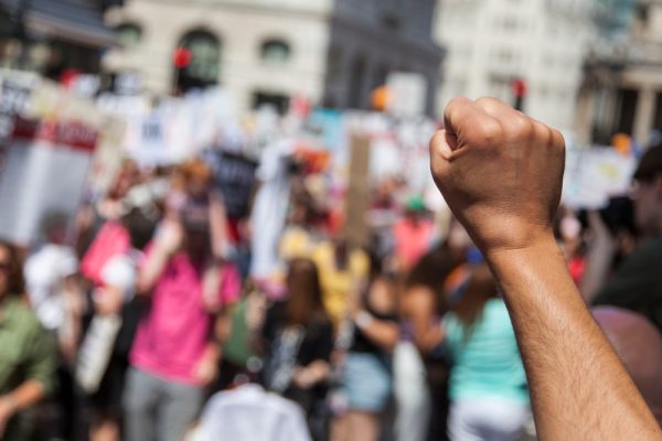 raised fist in forground at a protest