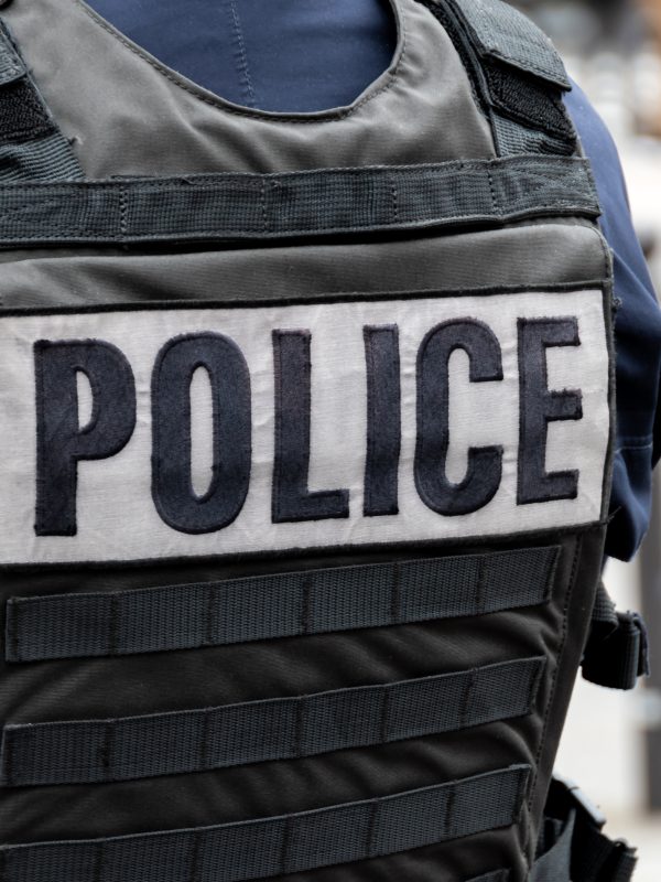 A person wearing a bulletproof vest with the word police across the back.