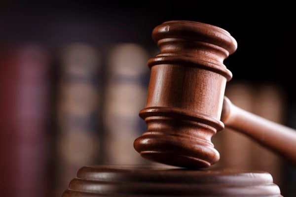 A judge's gavel with law books behind on a shelf behind it.