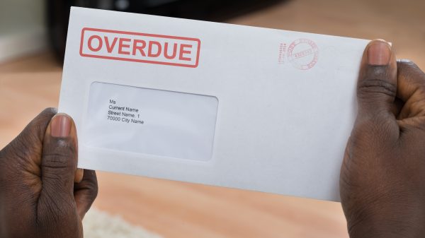 Close-up Of Person's Hand Holding Overdue Notice