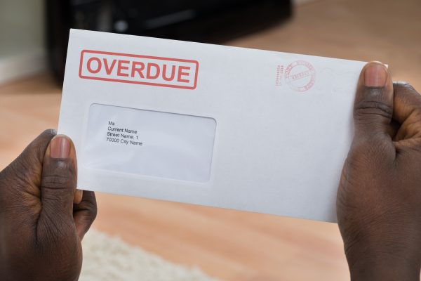 Close-up Of Person's Hand Holding Overdue Notice