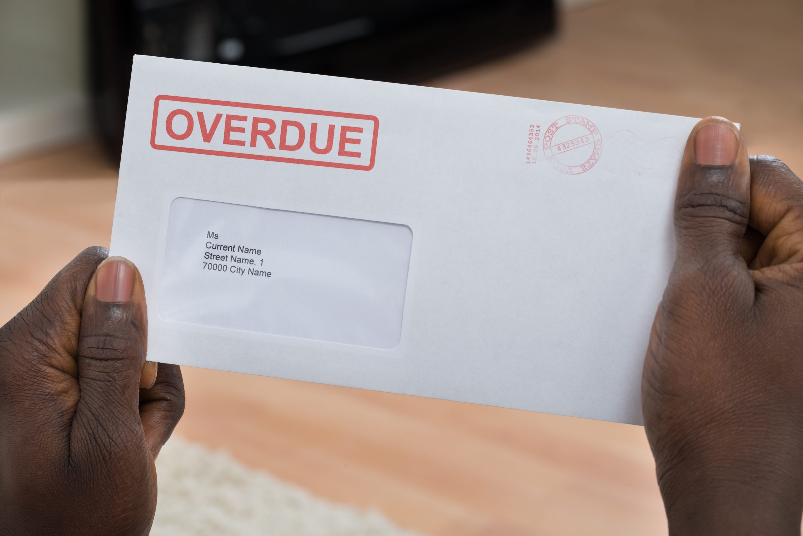 Close-up Of Person's Hand Holding Overdue Notice