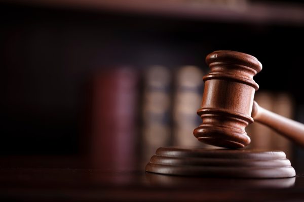 A gavel with a bookcase behind it.