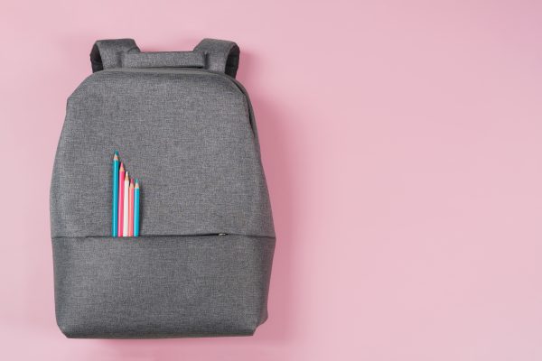 backpack on pink background with pencils in pink and blue