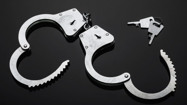 Silver handcuffs against black background.