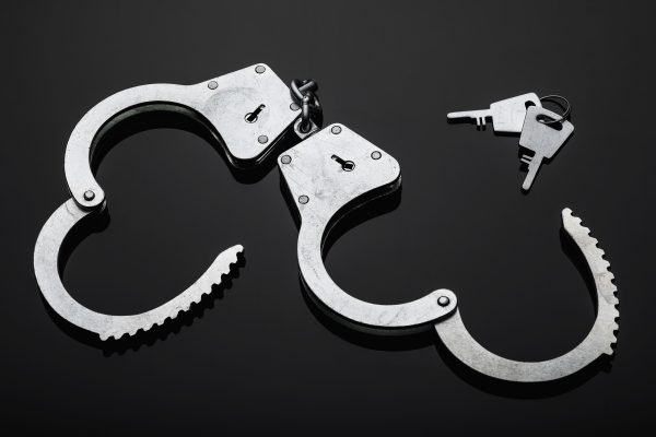 Silver handcuffs against black background.