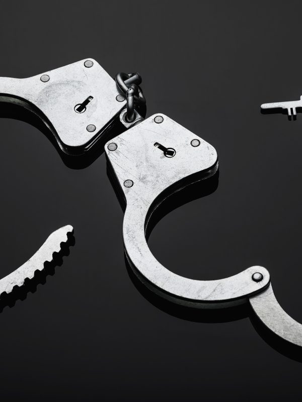 Silver handcuffs against black background.