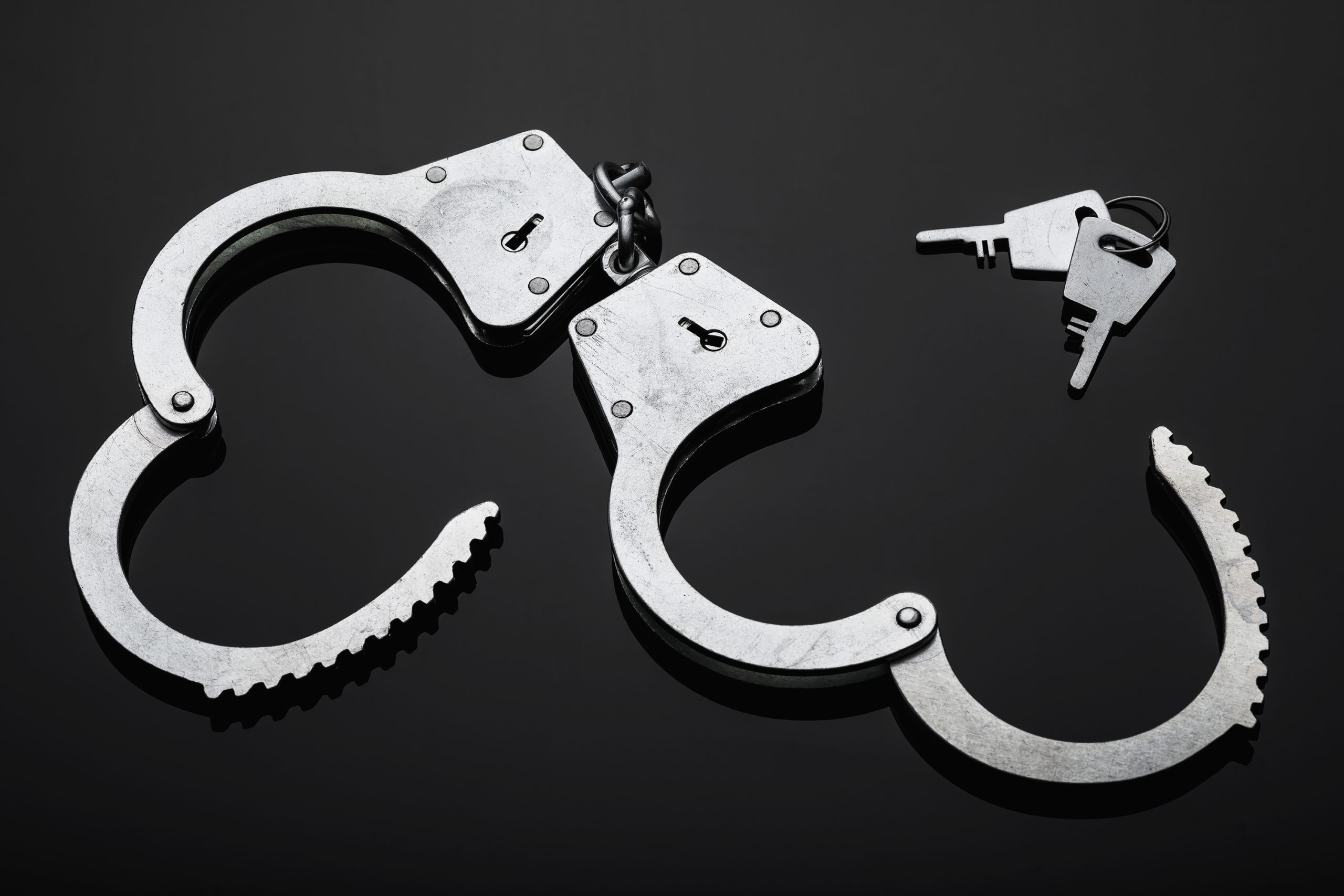 Silver handcuffs against black background.