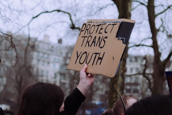 person holding a sign that says "Protect trans youth"