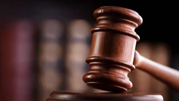 A gavel with a bookcase behind it.