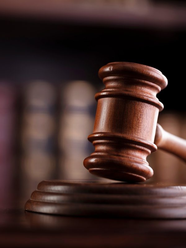 A gavel with a bookcase behind it.