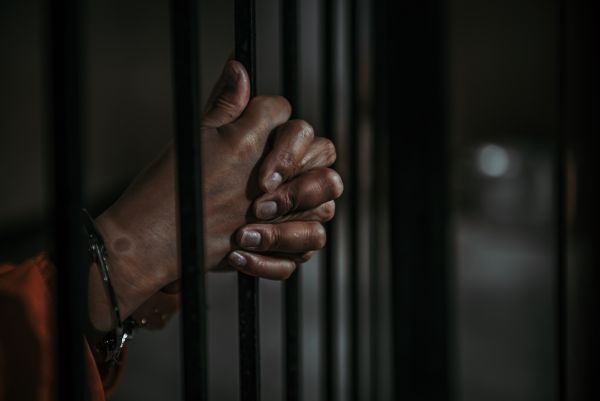 prisoner's hands behind bars