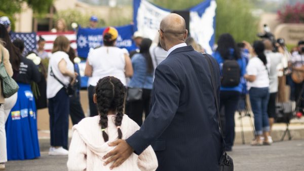 A man and girl at a rally in support of people losing their TPS status.