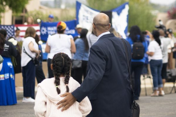 A man and girl at a rally in support of people losing their TPS status.