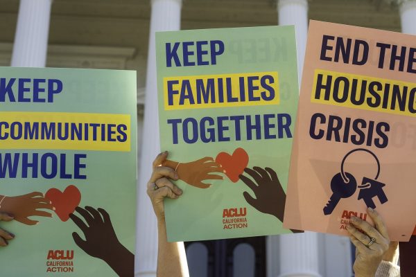 Placards reading "Keep Families Together;" "Keep Communities Whole;" and "End the Housing Crisis"